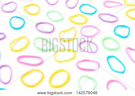 Surface covered with multiple colorful resin loom bands over the white background, shallow depth of field composition