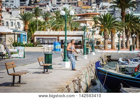 SITIA, CRETE, GREECE - JUNE 2016: Man mooring his boat near pier of Sitia town on Crete island