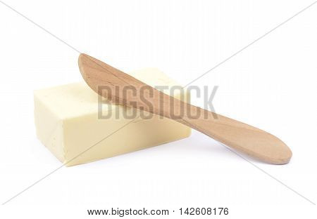Wooden knife over a briquette piece of a butter, composition isolated over the white background
