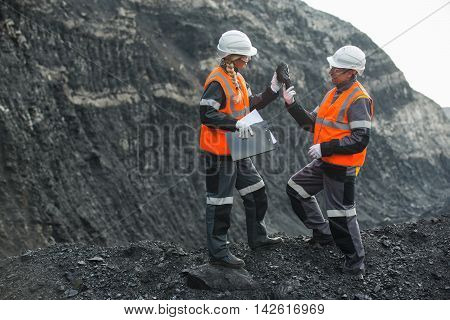 Two speacialists examining coal at an open pit