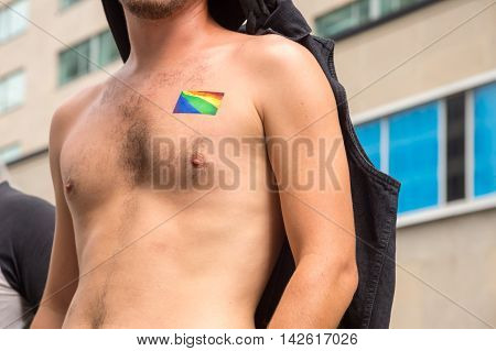Male chest with a gay rainbow flag sticker on the upper chest