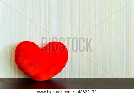 Red fabric heart on a wooden surface wenge color on the background wall with texture in a vertical strip. Love concept. Background with copy space.