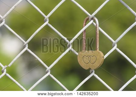 Closeup rusty heart shaped padlock locked on iron chain