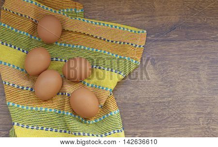 Raw eggs on a yellow fabric on a wooden table