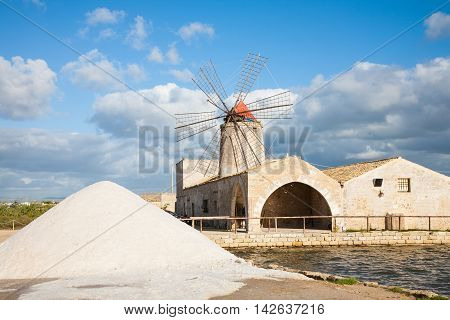A salt pan windmill and heap of sea salt near Trapani in western Sicily italy
