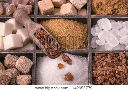 Assorted sugar and wooden scoop closeup toned