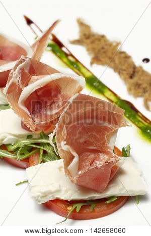 Appetizer - prosciutto, pork smoked cracklings, soft cheese,tomato, rocket, pesto bites, vertical, close up