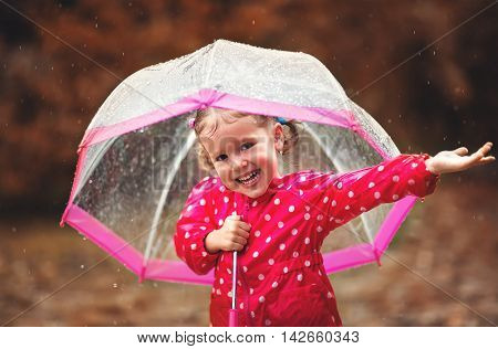 happy child girl laughing with an umbrella in the rain