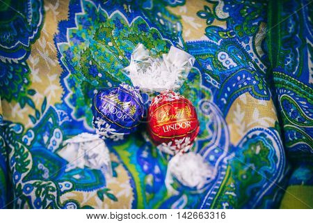 KILCHBERG SWITZERLAND - MARCH 20 2014: Two tasty Lindt Lindor chocolate truffle on a red luxury silk background.