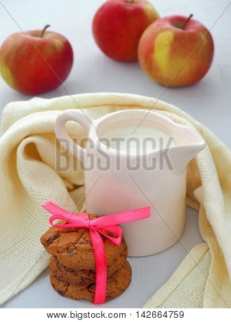 Milk Jug, Apples and Chocolate Chip Cookies on Wooden Background.