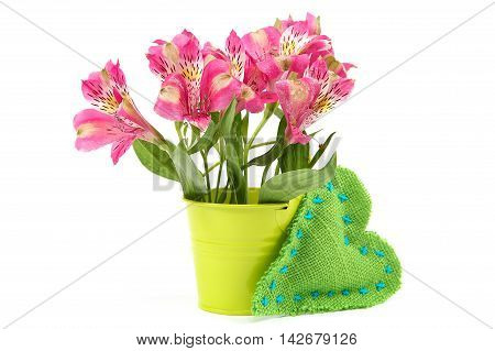 Pink lily flowers in a bucket and cushion heart isolated on white background.