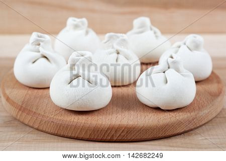 Manti dumplings on the a wooden board.