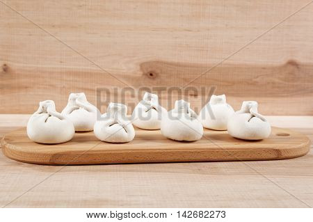 Manti dumplings on the a wooden board.
