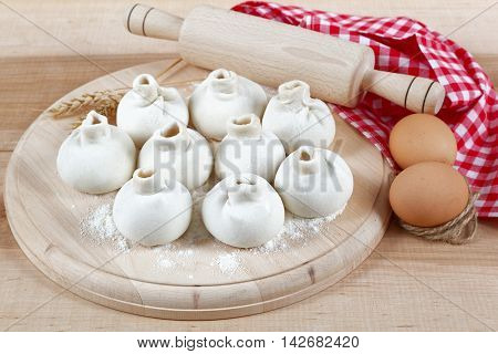 Baking ingredients for cooking manti dumplings on a wooden board.