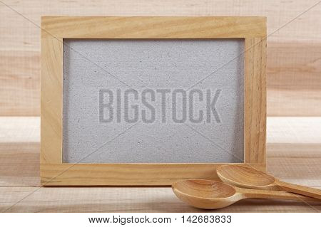 Kitchen utensils and wooden frame on a wooden board.