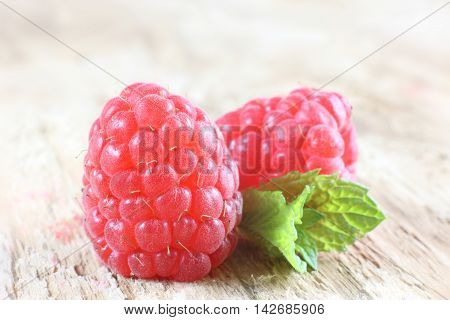 Red ripe raspberries and mint leaf on wooden background
