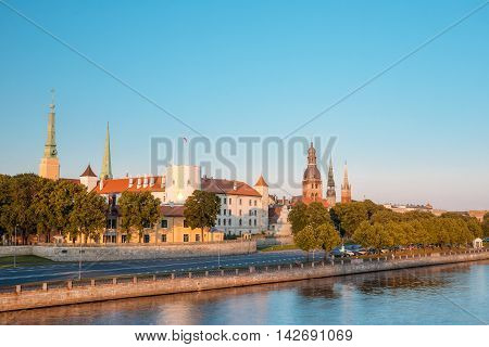 Scenic View To Promenad Of Daugava, In Riga, Latvia. Old Church Towers And Medieval Castle On Background. Seafront Named Ab Dambis. Evening  View With Blue Sky. Travel Destination. Urban View