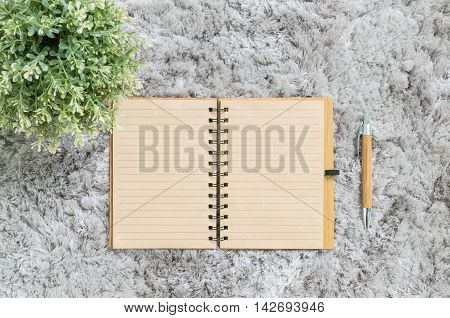 Closeup brown note book with brown pen on gray fabric capet textured background