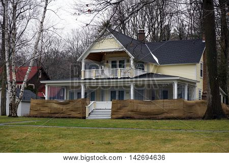WEQUETONSING, MICHIGAN / UNITED STATES - DECEMBER 22, 2015: An elegant yellow Victorian home with a wraparound front porch and a balcony  in Wequetonsing.