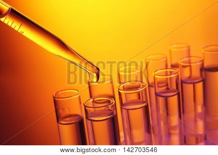 Close up of a pipette dropping a  sample into a test tube on colourful background