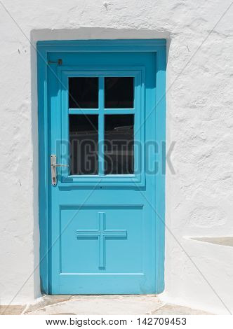 Blue traditional closed church door on a white wall from the Greek islands if Greece