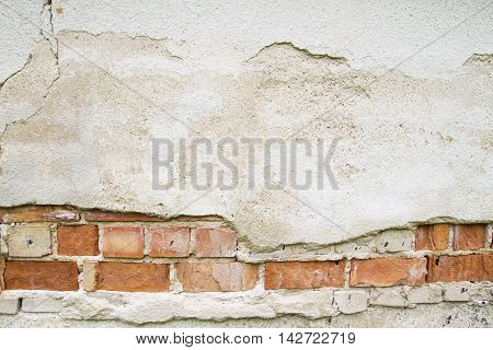 Broken vintage bricklaying wall fragment from old red clay bricks and damaged plaster background texture