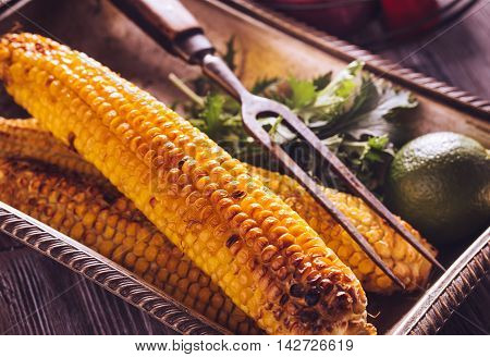 Baked corn in vintage tray with lime and herbs. Shallow depth of field