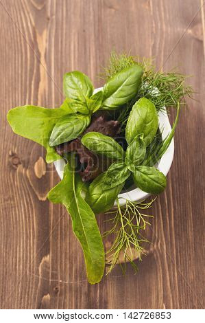 Basil and lettuce  in mortar top view on table