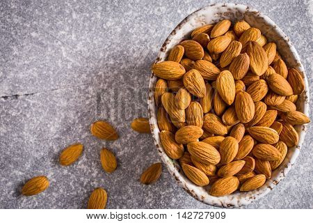 Bowl of almonds on stone background top view
