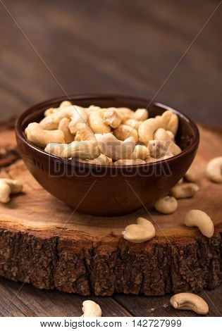 Bowl of fresh cashew on wood cut