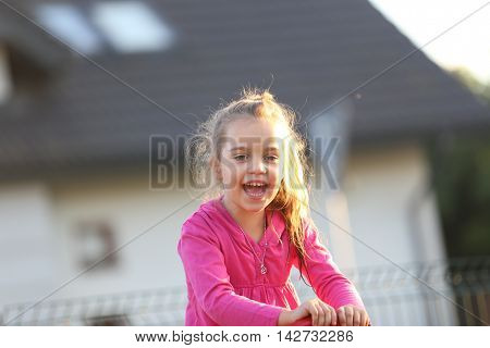 little girl wearing pink shirt lauging and playing at a playground
