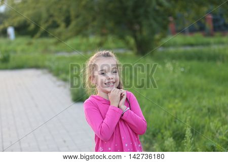little girl wearing pink shirt lauging and playing at a playground