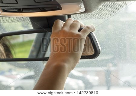 in the car the girl adjusts the rear view mirror