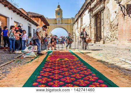 Antigua Guatemala - March 25 2016: Locals make dyed sawdust Good Friday carpet in popular street with arch for procession in colonial town with most famous Holy Week celebrations in Latin America.