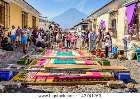 Antigua Guatemala - March 25 2016: Locals make dyed sawdust Good Friday carpet in street with Agua volcano behind for procession in colonial town with most famous Holy Week celebrations in Latin America.