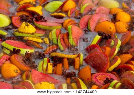 Cooking fruits and spices mulled wine in a large bowl