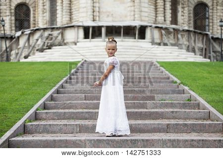 Portrait of a beautiful young little girl in white gown, summer outdoors