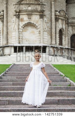 Portrait of a beautiful young little girl in white gown, summer outdoors