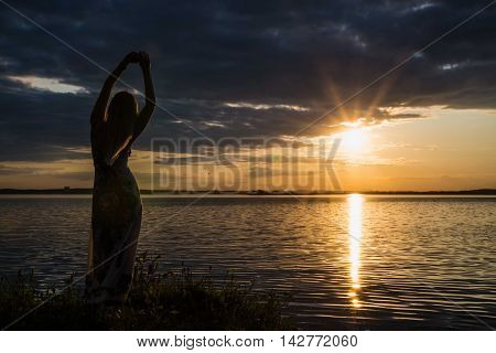 Young woman admires the sunset on the shore