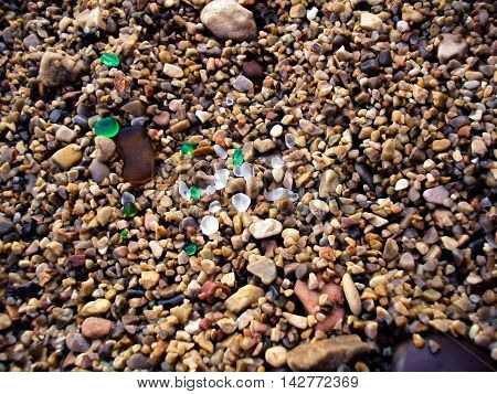 Multi-colored sea pebbles with glass pieces on the beach