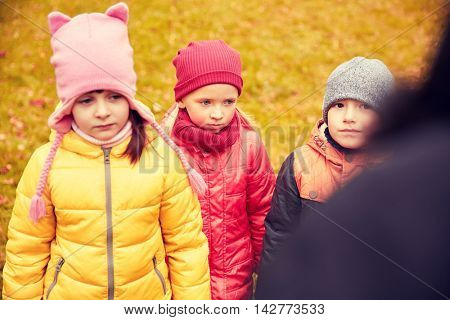 childhood, leisure, friendship and people concept - group of sad kids being blamed for misbehavior in autumn park