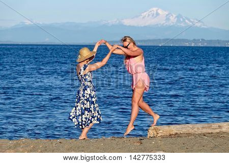 Two women on beach having fun. Centennial Beach at Boundary Bay Regional Park Tsawwassen British Columbia Canada.