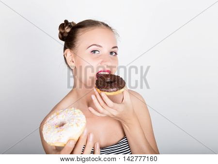 young woman in bright makeup eating a tasty donut with icing. Funny joyful woman with sweets, dessert. dieting concept. junk food. girl licking their fingers.
