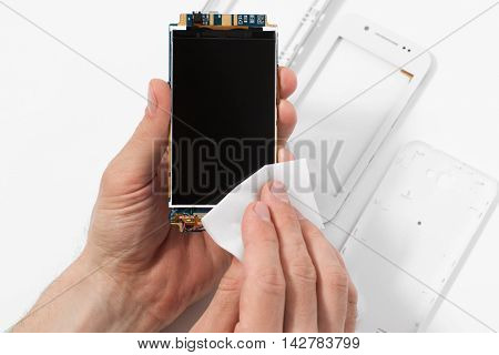 Repairman cleaning smartphone screen, taken apart case. Disassembled phone in repair service, white background, electronics recovery concept