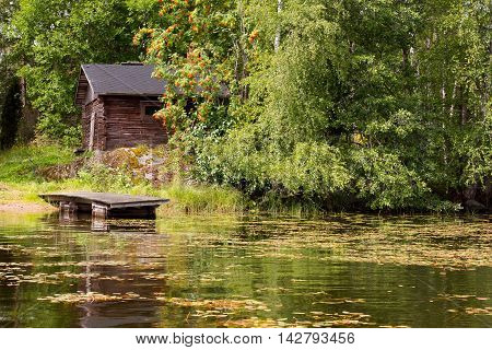 An old lakeside sauna hidden behind vegetation