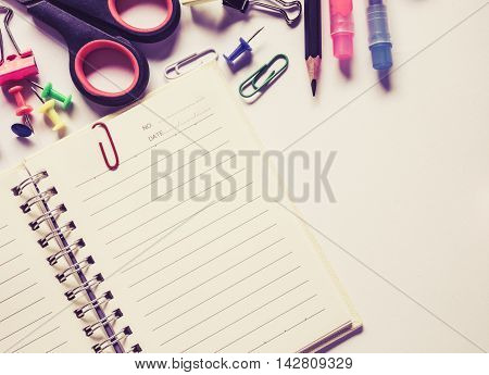Top view notebook and office suplies on wood table made soft focus style