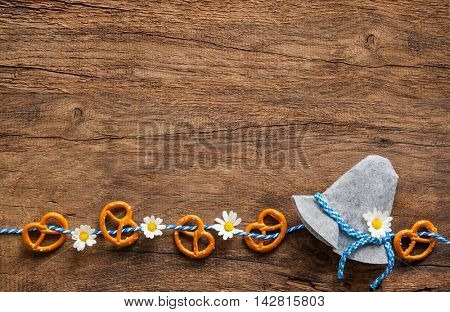 Border of pretzels and daisies with Bavarian hat on rustic wooden background with copy space for Oktoberfest