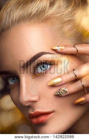 Beauty blonde model sexy girl face. Beautiful Fashion woman with perfect golden makeup, nail art manicure and accessories. Holiday Fashion art portrait