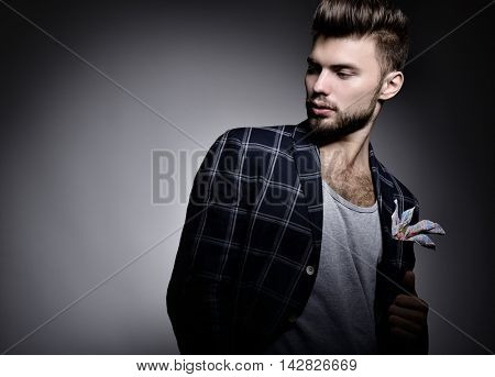 Portrait of handsome modern stylish man over gray background. Hypster gay in studio looking right at copyspace