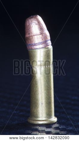 Rimfire cartridge bent in the middle on a graphite background